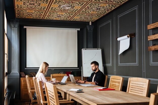 Colegas felizes sentados perto do café enquanto trabalhava com laptops