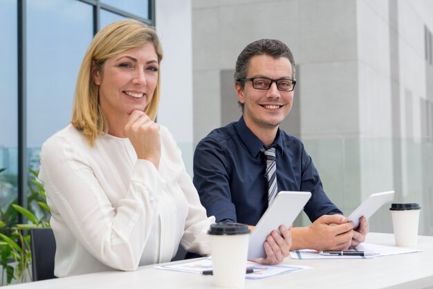 Colegas masculinos e fêmeas de sorriso que trabalham no café exterior.