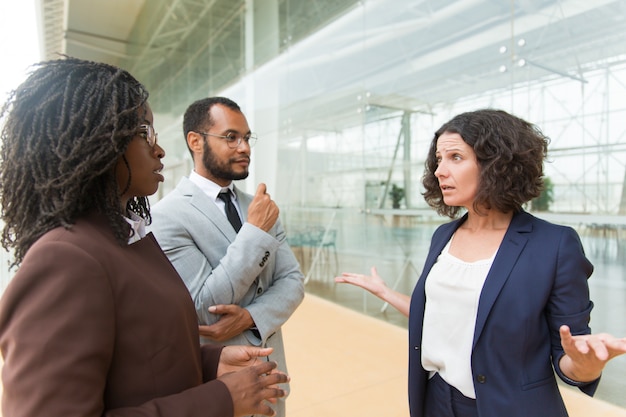 Foto grátis colegas multiétnicos animados discutindo fora