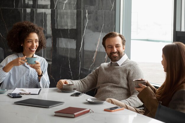 Colegas sorridentes com xícaras de café no trabalho