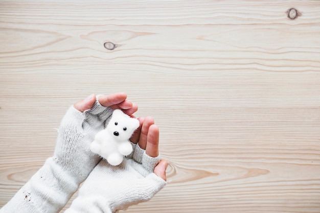 Colheita de mãos em luvas segurando urso branco