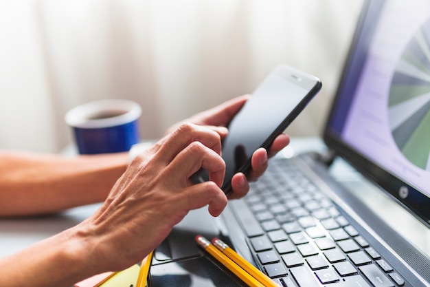 Colheita de mãos navegando smartphone no escritório