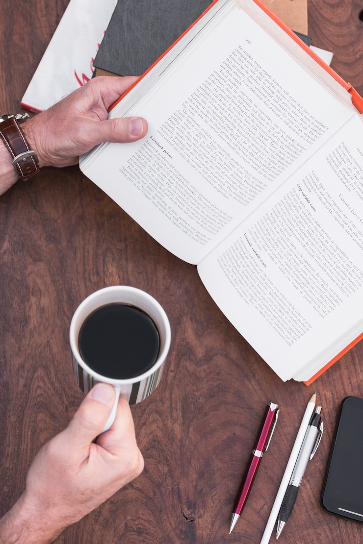 Foto grátis colheita de mãos segurando o livro e café