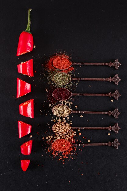 colher de metal com várias especiarias de pimenta em fatias de pimenta vermelha vista superior