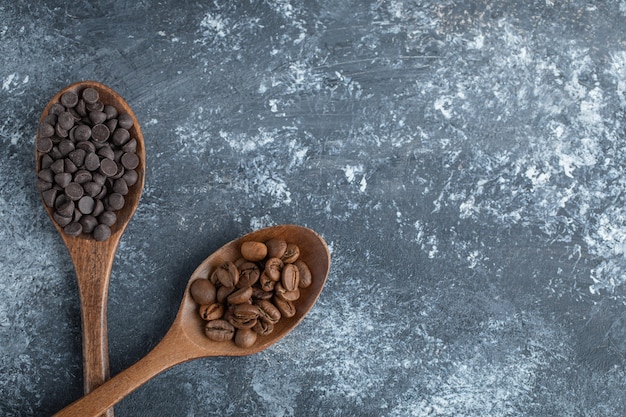 Colheres de madeira com gotas de chocolate e grãos de café.