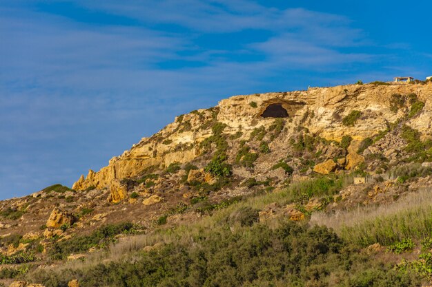 Colina rochosa com muitas plantas verdes sob o lindo céu azul claro