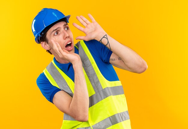 Com medo de olhar para o lado, jovem construtor de uniforme