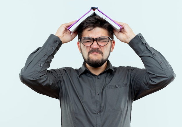 Foto grátis com os olhos fechados, zangado jovem empresário com óculos, a cabeça coberta com um livro isolado