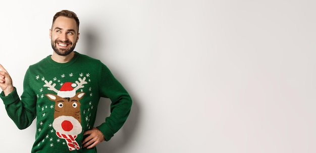 Comemoração de ano novo e conceito de férias de inverno bonito homem sorridente em suéter verde de natal poi