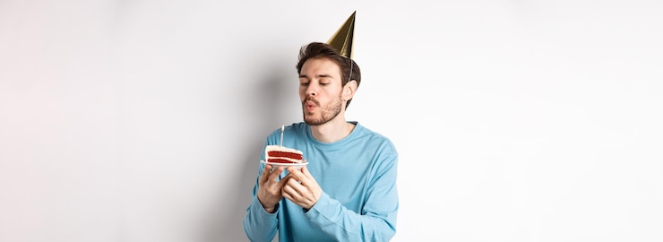 Foto grátis comemoração e conceito de férias feliz cara bobo soprando vela no bolo e fazendo desejo em pé