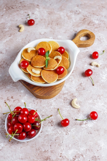 Comida da moda - mini cereal panqueca. Pilha de panquecas de cereais com frutas e nozes.