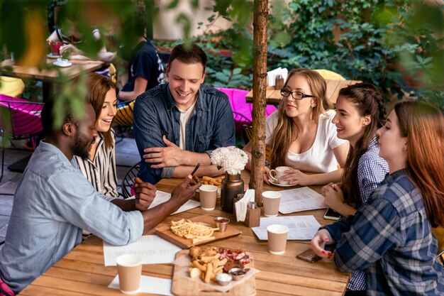 Comida deliciosa na mesa de uma reunião amigável dos melhores amigos no acolhedor restaurante ao ar livre