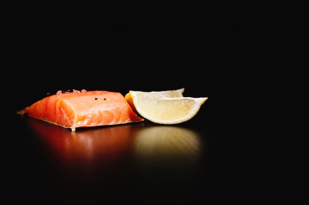 Comida fresca, saborosa e saudável. Salmão vermelho e limão no fundo preto isolado