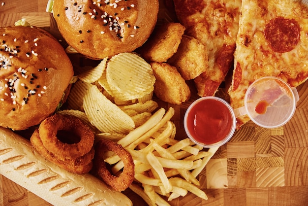 Comida insalubre e lixo. diferentes tipos de fast food na mesa, close-up