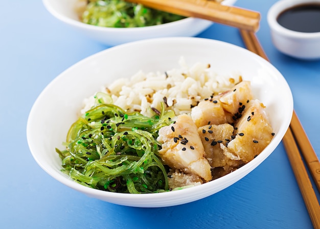 Comida japonesa tigela de arroz, peixe branco cozido e wakame chuka ou salada de algas.