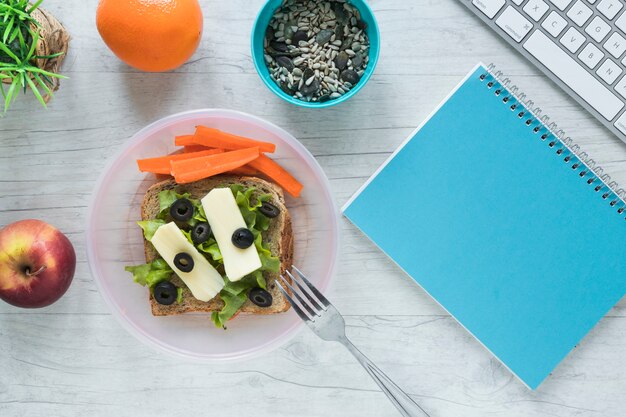 Comida saudável com livro espiral e teclado de computador sem fio na mesa