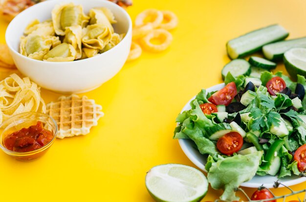 Comida saudável vs alimentos pouco saudáveis na mesa amarela