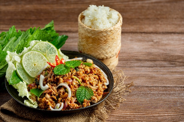 Comida tailandesa com carne de porco picante picada servida com acompanhamentos e arroz pegajoso