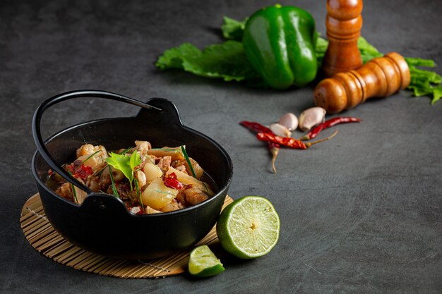 Comida tailandesa com sopa picante de perna de porco em tigela preta