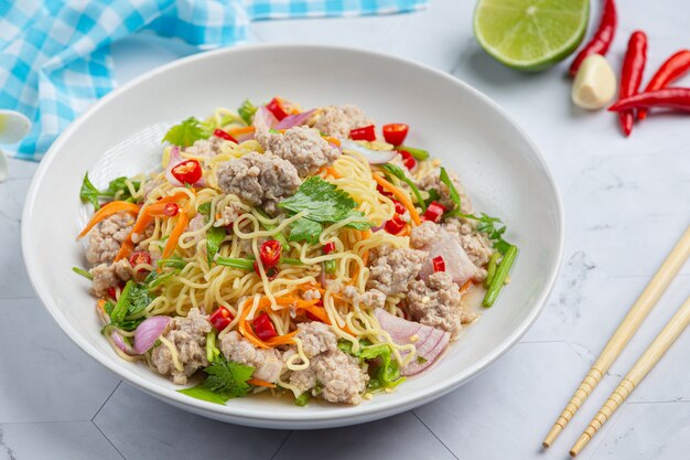 Comida tailandesa. Salada picante de macarrão instantâneo com carne de porco picada