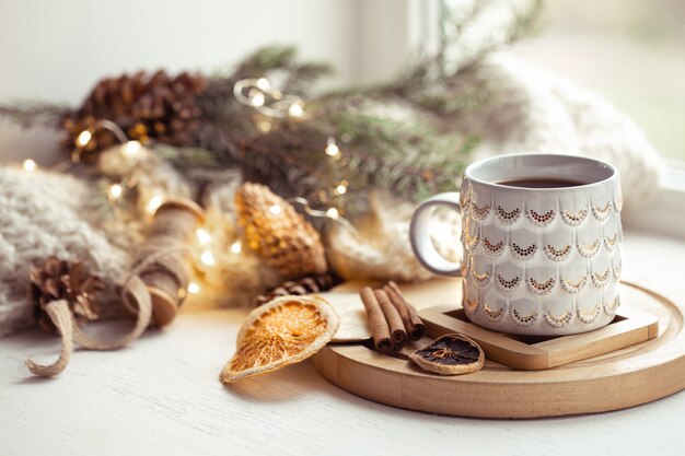 Composição aconchegante com uma xícara de Natal com uma bebida quente e canela em um fundo desfocado. Conceito de aconchego de inverno em casa.