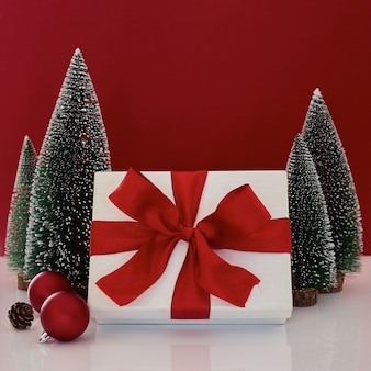Composição com caixa de presente de natal com decoração de árvore de natal em fundo vermelho