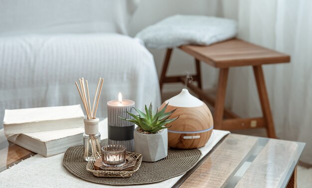 Composição com paus de incenso, difusor, velas e livros na mesa do interior da sala.