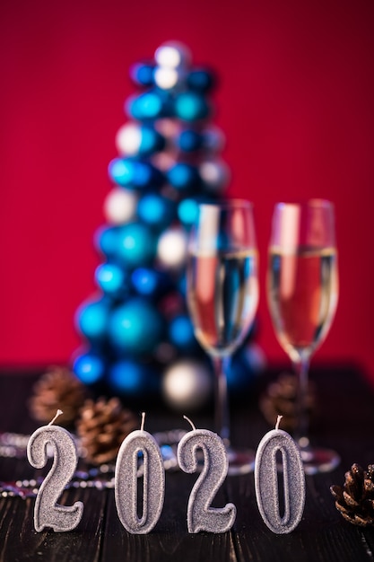 Composição de ano novo 2020 com champanhe e espaço para texto contra árvore e luzes de Natal borradas. Conceito de ano novo e natal