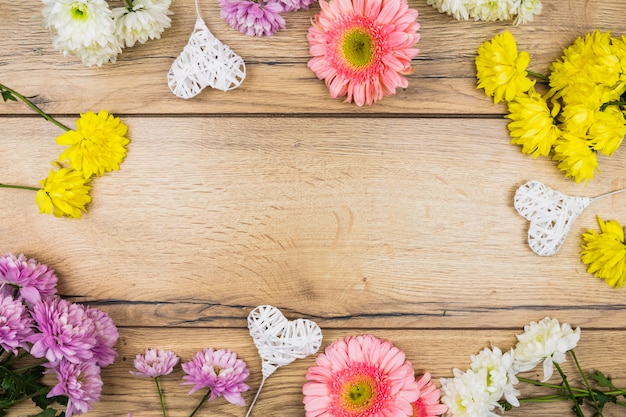 Composição de flores frescas perto de corações ornamentais em varinhas