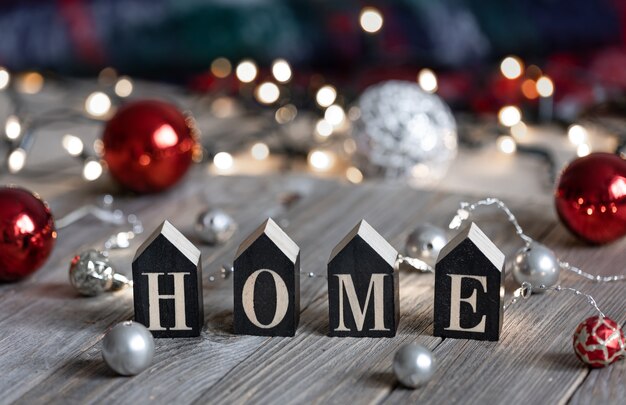 Foto grátis composição de inverno com a palavra decorativa casa e bolas de natal em um fundo desfocado com bokeh.