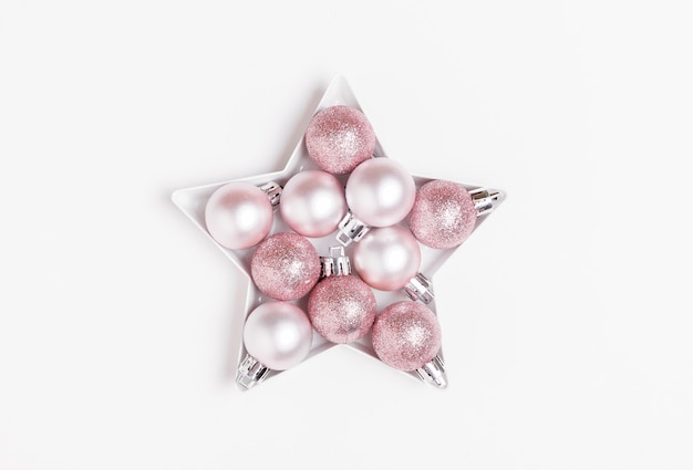 Composição de natal. bolas de natal rosa e prata dispostas em forma de uma estrela no fundo branco.