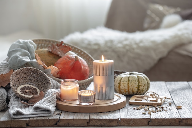 Composição de outono aconchegante com velas e abóboras no interior de uma casa.
