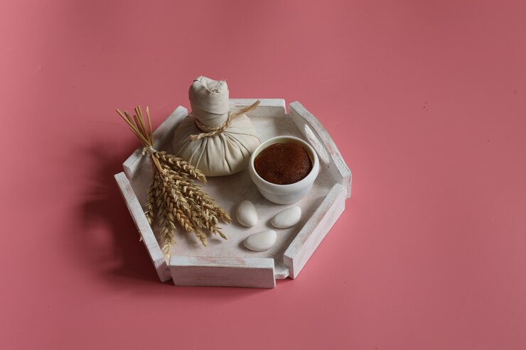Foto grátis composição de spa com bolsa de ervas e esfoliante natural em um fundo rosa