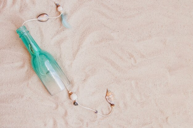 Composição de verão com areia, garrafa e espaço em branco