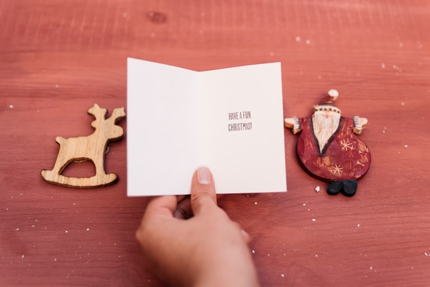 Composição do Natal com mão segurando o cartão de Natal