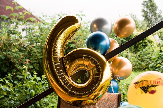 Composição dos balões de hélio dourado e azul - grande figura de seis na cor dourada do lado de fora - fundo desfocado