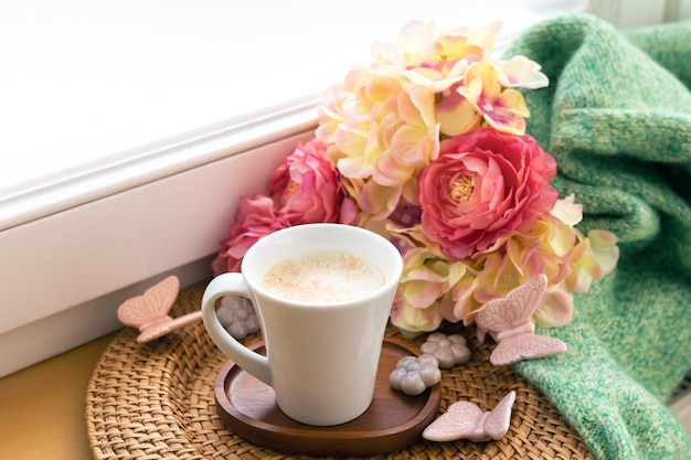 Composição em casa com uma xícara de flores de café e um elemento de malha
