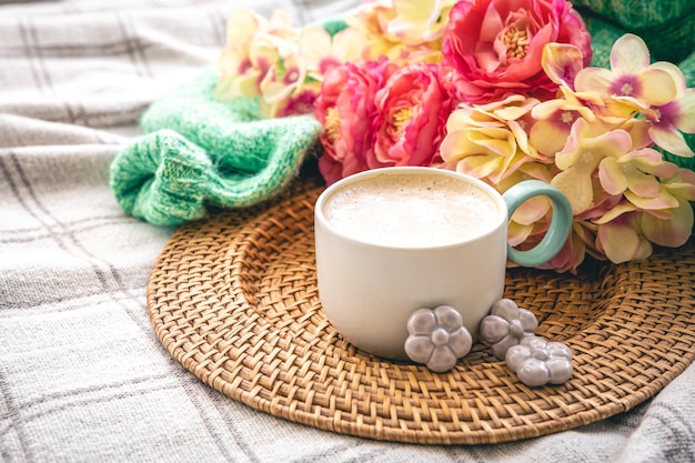 Composição em casa com uma xícara de flores de café e um elemento de malha