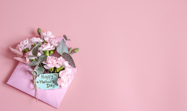 Composição festiva com um envelope com flores frescas e a inscrição feliz dia das mães plana leigos.