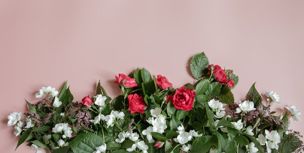 Composição plana leiga com flores frescas em fundo rosa.