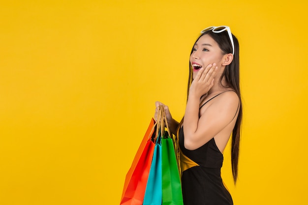 Compra linda mulher segurando um saco de papel colorido em um amarelo.