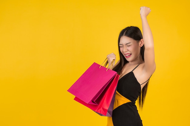 Compra linda mulher segurando um saco de papel colorido em um amarelo.