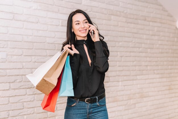 Comprador contemporâneo com sacos falando no telefone