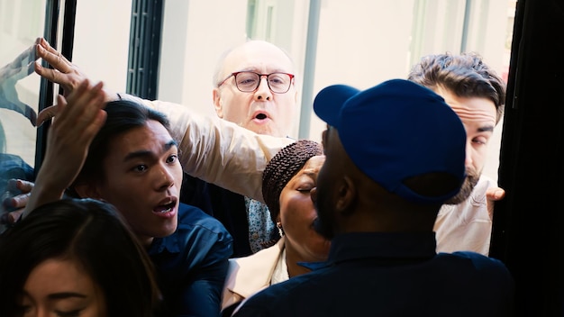 Foto grátis compradores malucos invadem lojas durante as promoções da black friday no shopping, empurrando o segurança e pedindo acesso à loja. pessoas ansiosas e agressivas do lado de fora da porta da frente. tiro portátil.