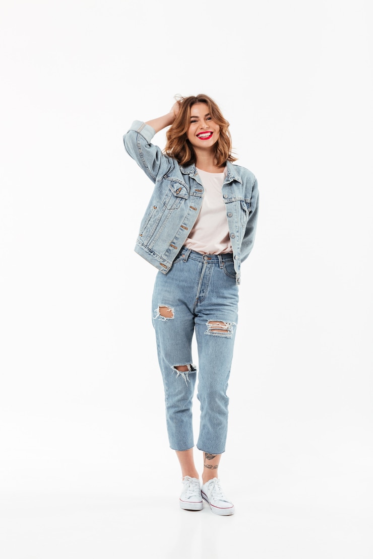 Foto grátis comprimento total mulher alegre em roupas jeans posando sobre parede branca
