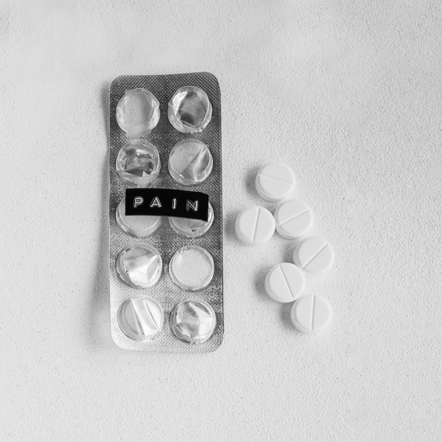Comprimidos brancos, além de bolha vazia, mostrando o rótulo de dor