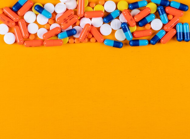 Comprimidos coloridos em uma superfície laranja