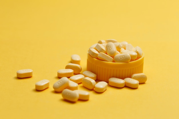 Foto grátis comprimidos de vitamina b em fundo amarelo