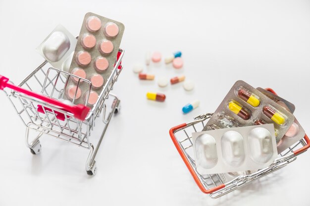 Comprimidos e medicina bolhas dentro do carrinho de compras dois no fundo branco