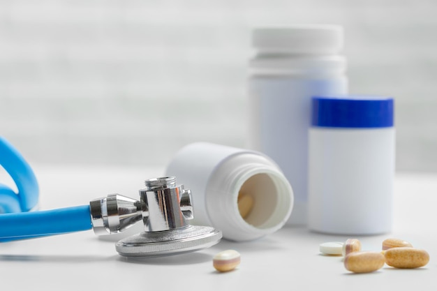 Comprimidos ou cápsulas e estetoscópio sobre os cuidados de saúde de conceito de mesa branca